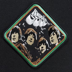 Op de afbeelding: Geborduurde patch met de albumhoes van The Beatles' "Rubber Soul". De patch heeft een zwarte achtergrond met een ruitvorm, een groene en oranje rand en afbeeldingen van de bandleden. De woorden "Rubber Soul" zijn in het wit.