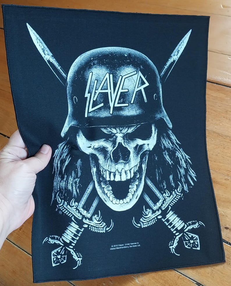 May include: Black patch featuring a skull wearing a helmet with the word "SLAYER" in white. Two crossed swords are behind the skull. The patch is rectangular and made of fabric.