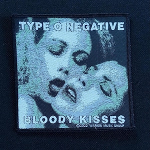May include: Square patch featuring the text "TYPE O NEGATIVE" above the words "BLOODY KISSES". The patch has a black border and a light blue and white image of two faces kissing. The text "©2022 WARNER MUSIC GROUP" is at the bottom.