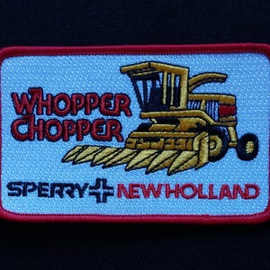 May include: An embroidered patch in red, white and blue featuring a yellow and black combine harvester. The patch reads "Whipper Chopper" and "Sperry New Holland".