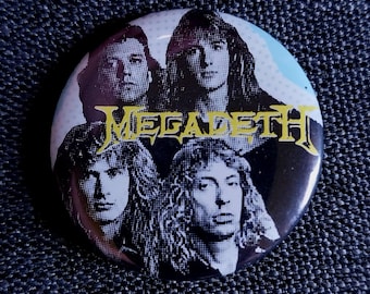 May include: Round button featuring a black and white image of a band with the word "MEGADETH" in yellow. The button has a glossy finish and is set against a dark blue denim background.