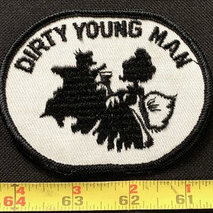 May include: White oval patch with black embroidered text "Dirty Young Man" and a black silhouette of two figures.