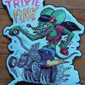 May include: Embroidered patch with a green rat-like character in a hot rod. The text "TRIXIE FINK" is at the top, with "MAN EATER" on the car. The character holds an 8-ball and a heart. The design includes flames and smoke.