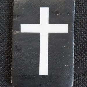May include: A white cross on a black background. The cross is a religious symbol.