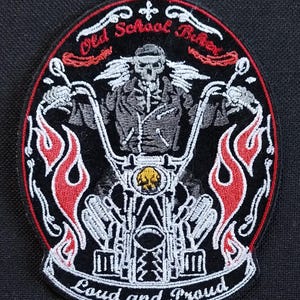 May include: Embroidered patch featuring a skeleton riding a motorcycle with flames on either side. The patch is oval shaped and has the text "Old School Rider" and "Loud and Proud" on it.