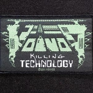 Pode incluir: Patch retangular preto com o texto "ZE BAND" em uma fonte estilizada verde claro. Abaixo, as palavras "KILLING TECHNOLOGY" estão em branco, com "©2011 VOIVOD" na parte inferior. O patch tem uma borda preta e um fundo preto.
