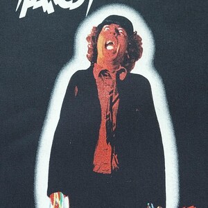 May include: Black t-shirt featuring the band AC/DC with the album title "Powerage." The design includes a stylized image of a man with his mouth open, and the band's logo in white.
