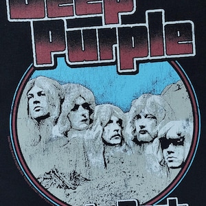 May include: Black t-shirt featuring the band Deep Purple. The design includes the band's name in a red and white font, with a blue circle containing the band members' faces. The words "in Rock" are at the bottom.