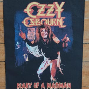 May include: Black rectangular patch featuring Ozzy Osbourne with the text "OZZY OSBOURNE" in gold and "DIARY OF A MADMAN" in red. The image shows Osbourne in a black shirt and white pants.