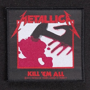 May include: Black square patch featuring the band name "METALLICA" in red, with a graphic of a hand holding a hammer over a red shape. The text "KILL 'EM ALL" is below the graphic. Copyright information is at the bottom.