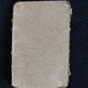 May include: A blank, off-white, rectangular card with a slightly rough texture. The card is made of paper and has a slightly frayed edge.