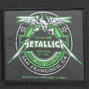 Pode incluir: Patch quadrado preto com o logotipo da Metallica, apresentando um design de caveira e asas em verde e branco. O texto inclui "Since 1981", "100% Fuel by Vol", "Seek and Destroy" e "San Francisco, CA".