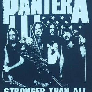 May include: Black t-shirt featuring the band Pantera with the text "PANTERA" above and "STRONGER THAN ALL" below. The image includes a band photo and stars.