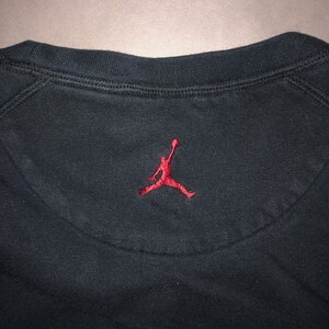 May include: Black sweatshirt with a red embroidered Jumpman logo on the back.
