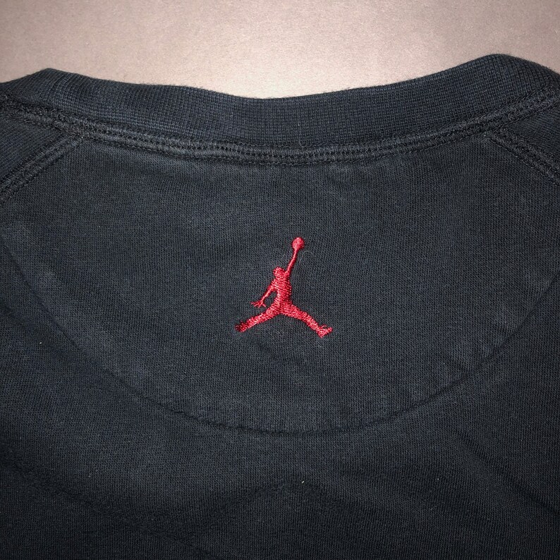 May include: Black sweatshirt with a red embroidered Jumpman logo on the back.