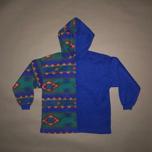 May include: A blue fleece hoodie with a geometric pattern on one side and solid blue on the other. The pattern is in shades of green, red, yellow, and blue.