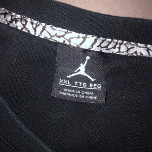 May include: Black t-shirt with a white Jordan logo and text that reads "XXL TTG EEG Made in China Fabrique en Chine".