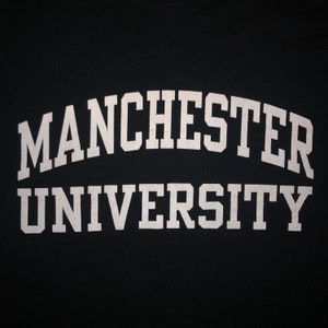 May include: A black t-shirt with white text that reads "MANCHESTER UNIVERSITY" in an arched font.