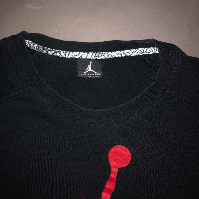 May include: Black t-shirt with a red Jumpman logo and a white tag that says "Nike Air Jordan" on the front.