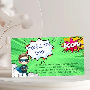 May include: A baby shower invitation card with a green background and a comic book theme. The card features a superhero baby illustration, speech bubbles with the words "books for baby" and "BOOM!", and text requesting a book instead of a card.