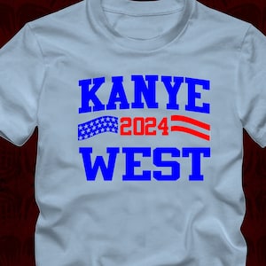 May include: Light blue t-shirt with the text "KANYE 2024 WEST" in blue and red letters. An American flag graphic is above the text.