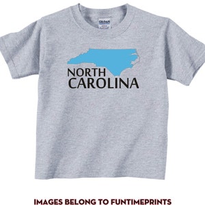 May include: A gray t-shirt with a blue outline of the state of North Carolina and the text "NORTH CAROLINA" in black.