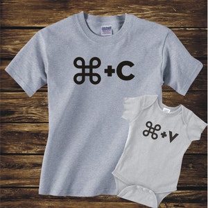 May include: A gray t-shirt with the text "⌘ + C" and a gray baby onesie with the text "⌘ + V".
