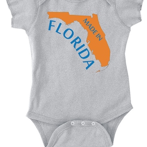 May include: Gray baby onesie with an orange outline of the state of Florida and the text "Made in Florida" in blue.