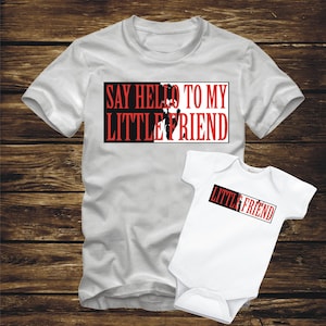 May include: A white t-shirt with the text "Say Hello To My Little Friend" in red and black. A white baby onesie with the text "Little Friend" in red and black.