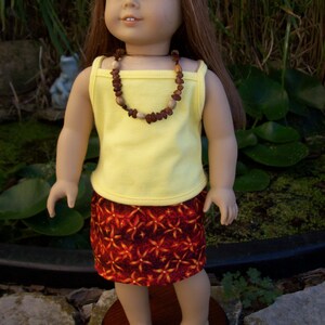 Se adapta a muñecas de 18&quot; como American girl o de 15&quot; como Bitty Baby. camisa amarilla, falda multicolor y collar de madera.