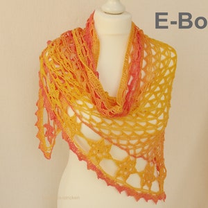 May include: A crocheted shawl in a gradient of pink and yellow. The shawl is draped over a white mannequin. The text "E-Book" is visible in the top right corner of the image.