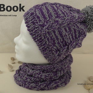 May include: A knitted purple and grey hat and loop scarf set with a grey pom-pom. The hat and scarf are displayed on a white mannequin head. The text "E-Book Wohlfühlmütze mit Loop" is visible in the upper left corner.