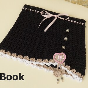 May include: Black crochet skirt with a brown and white lace trim, pink ribbon, and a heart-shaped embellishment. The skirt has three silver buttons and the text "E-Book" is visible at the bottom of the image.