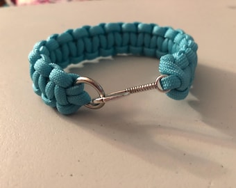 May include: A turquoise paracord bracelet with a silver clasp.
