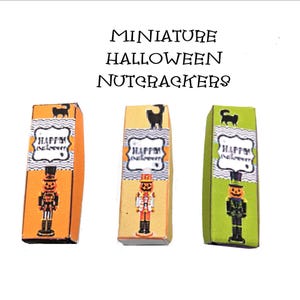 May include: Three miniature rectangular boxes labeled MINIATURE HALLOWEEN NUTCRACKERS. Each box features a black cat silhouette, a label reading HAPPY HALLOWEEN, and a graphic of a pumpkin-headed nutcracker in orange, yellow, and green.