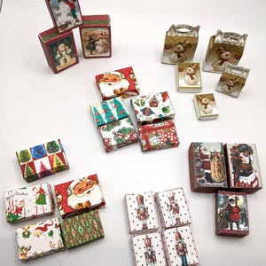 May include: A collection of small, decorative Christmas-themed boxes. The boxes feature various festive designs, including Santa Claus, snowmen, Christmas trees, and nutcrackers. The color palette includes red, green, white, and gold.