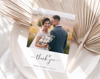 May include: A white thank you card featuring a photograph of a bride and groom. The card includes the text "thank you" in cursive with a small heart above the word "you". The card also displays the text "Chloe & John - 08.06.23" printed beneath the photo.