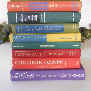 May include: A stack of ten hardcover books with various titles and authors. The books are arranged in a vertical stack, with the top book being green and the bottom book being purple. The titles of the books include "The Foolish Gentlewoman", "Seven Wonders of the World", "Being Safe", "Glendower Country", and "The Wines of America".