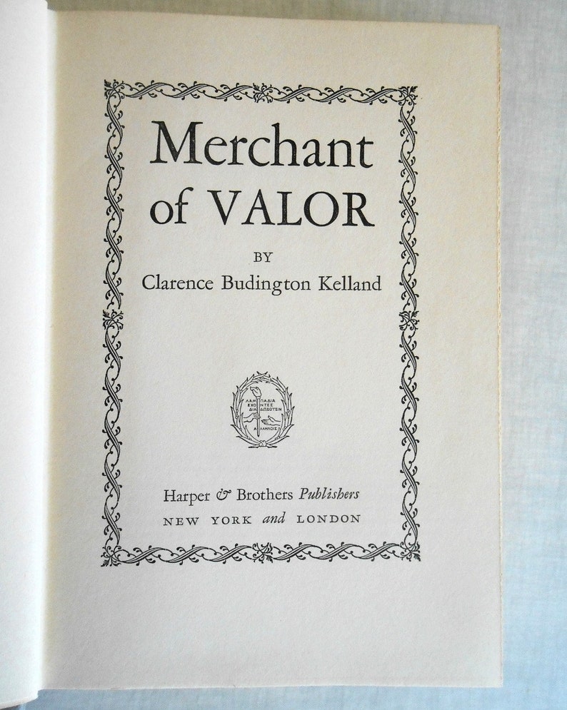 May include: Open book page featuring the title "Merchant of Valor" by Clarence Budington Kelland. The title is in a bold, serif font, framed by an ornate black and white border. The publisher's name and location are also visible.