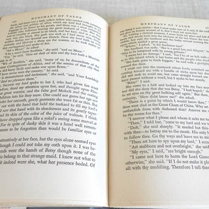 May include: Open book with aged, yellowed pages. The text is in black, with the title "Merchant of Valor" at the top. The book is open to two facing pages, with the text filling the pages.