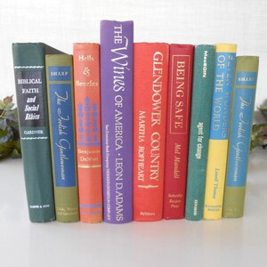 May include: A collection of ten vintage hardcover books with colorful spines and gold lettering. The books are arranged vertically on a white surface. The titles include "The Foolish Gentlewoman", "Hells & Benefits", "The Wines of America", "Glendower Country", "Being Safe", "Agent for Change", "Seven Wonders of the World", and "The Foolish Gentlewoman".