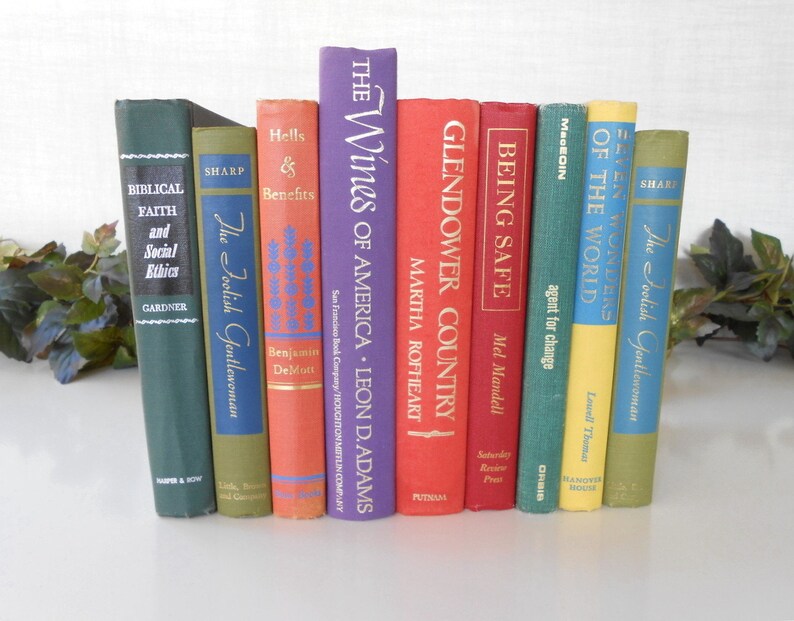 May include: A collection of ten vintage hardcover books with colorful spines and gold lettering. The books are arranged vertically on a white surface. The titles include "The Foolish Gentlewoman", "Hells & Benefits", "The Wines of America", "Glendower Country", "Being Safe", "Agent for Change", "Seven Wonders of the World", and "The Foolish Gentlewoman".