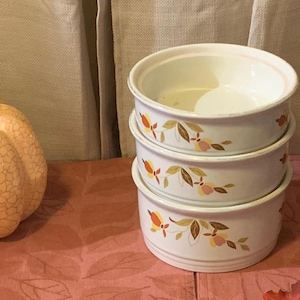 May include: Set of three white ceramic bowls with a fall leaf design in shades of orange, yellow, and brown. The bowls are stacked on top of each other.