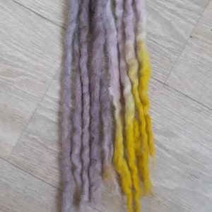 Könnte beinhalten: Ein Satz langer, synthetischer Dreadlocks mit einem Farbverlauf von Grau zu Gelb.