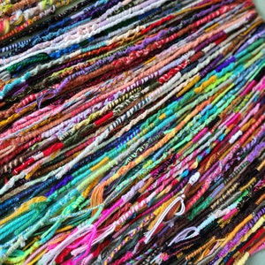 May include: A collection of colorful yarn strands, each tied together at one end, creating a vibrant and textured display.