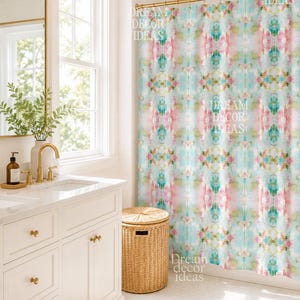 May include: A shower curtain featuring a repeating abstract watercolor pattern in shades of soft pink, teal, and yellow. The curtain hangs from a gold-toned rod and displays the text DREAM DECOR IDEAS printed repeatedly across the fabric surface.