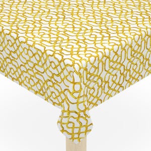 May include: A square table with a white tablecloth featuring a gold, interwoven pattern. The table has four light-colored wooden legs. The tablecloth drapes over the edges of the table.