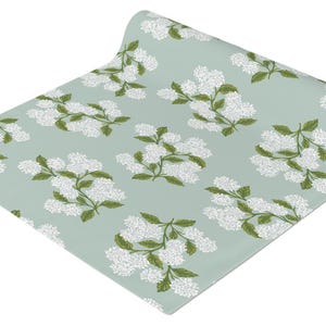 May include: A roll of light blue wrapping paper with a white floral pattern. The paper is rolled up and the end is visible.