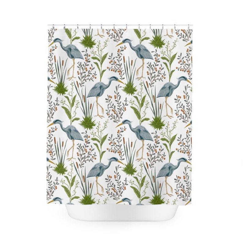 May include: A white shower curtain with a repeating pattern of blue herons standing in a marsh. The herons are surrounded by green reeds and brown berries.