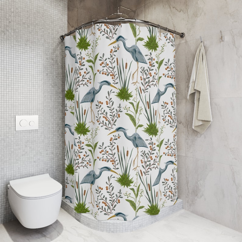 May include: A white shower curtain with a blue heron and green foliage pattern. The shower curtain is hung on a curved shower rod.